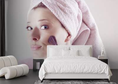 Beauty and make-up concept - Happy young beautiful woman applying makeup on face by brush Wall mural