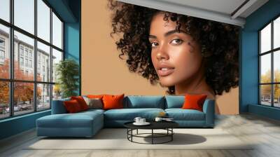 beauty portrait of a young woman with healthy curly hair and natural skin without makeup, on a beige background, skin and curly hair care concept Wall mural