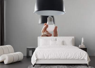 Changing the bulb for led bulb in floor lamp in black colour. On light gray background Wall mural