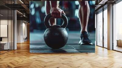 Closeup of athletic man holding black iron kettlebell in a crossfit training on fitness center or in a gym Wall mural