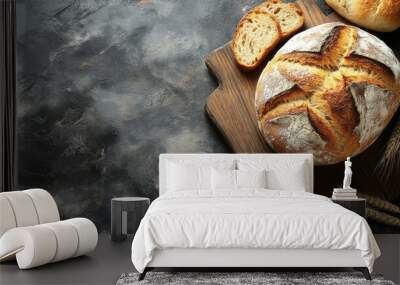 Freshly baked bread on dark textured surface, sliced ​​bread slices lying nearby on dark surface Wall mural