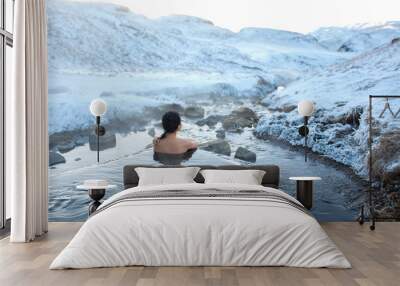 The girl bathes in a hot spring in the open air with a gorgeous view of the snowy mountains. Incredible iceland in winter Wall mural