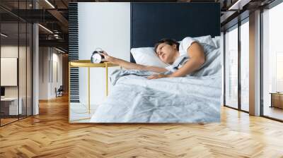 The girl turns off the annoying alarm clock to continue sleeping. Get some more sleep. It a hard morning. Time to wake up. Wall mural