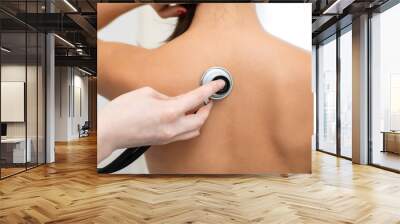 Woman doctor therapist listening with a stethoscope to a back, young female patient Wall mural