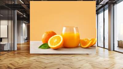 Close up of orange juice in a glass with oranges against trendy yellow background Wall mural