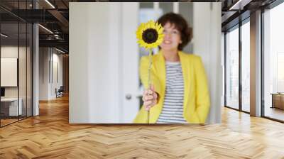 woman in a yellow jacket with a sunflower smile Wall mural