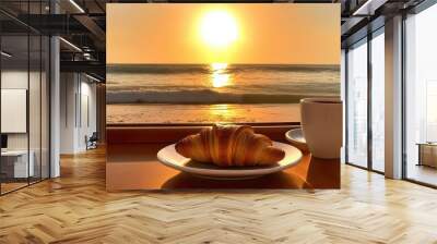 a table with a plate of croissants and a cup of coffee, sun set, at a tropical beach Wall mural