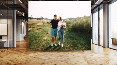 A young happy family, dad, mom and their little son, have a great time together on the nature Wall mural