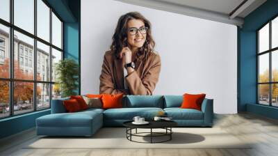 emotional portrait of a beautiful and smiling girl in a glasses which stands near a white wall. blan Wall mural