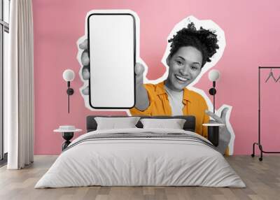 Excited happy black and white african american girl, holding smart phone in her hand with blank white mock-up screen for presentation, stands on isolated pink background, smiling. Cut out concept Wall mural