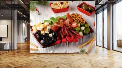 on a red rectangular plate: olives, red, green and yellow cheese, crackers, ham and salami, rectangular red saucers with green olives nearby, white wooden background, New Year, Christmas atmosphere, C Wall mural