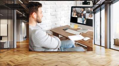 Online training. Young guy learns online by video conference in zoom app. On the screen, the teacher tells the information to him and other participants in the conference Wall mural