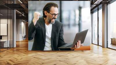 Overjoyed senior adult businessman is using laptop, receive good news. Excited mature entrepreneur got promotion on work or have done successful project, enjoy own results Wall mural