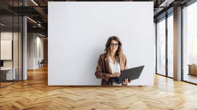 Smiling beautiful business woman in a glasses with a laptop in her hands in the office with copy space Wall mural