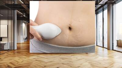 The girl after pregnancy restores the skin of the abdomen with a cream and a massager. Cellulite removal and treatment. Wall mural