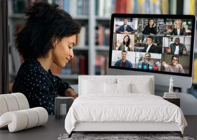 Video call, online conference using app and computer. African American female student, studying remotely, watches an online lecture, taking notes, multiracial smiling people on the computer screen Wall mural