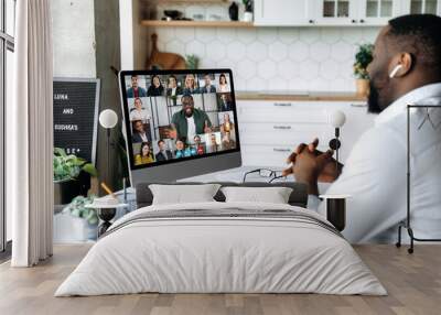 Video conference. online meeting. Intelligent African American business man sits at work desk at home, looks at the computer screen, communicates by video call with his partners, discuss a strategy Wall mural