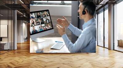 Virtuak business meeting online. Successful businessman is negotiating with multiracial business partners on a video conference using a computer while sitting at his workplace Wall mural