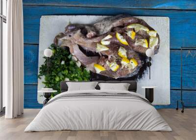 two raw fish steaks on a cutting board with greens and lemon on  Wall mural