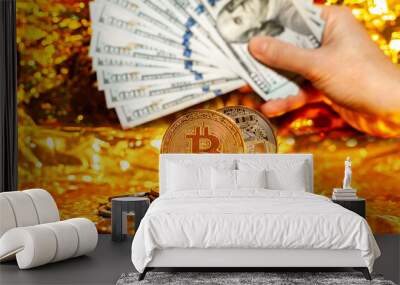 Two bitcoins on a stack of coins against a background of hundred-dollar bills arranged in a fan on a golden background Wall mural