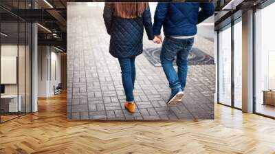 Young couple on a city street walking hand in hand Wall mural