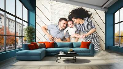 Young father, mother and cute baby lying on floor Wall mural