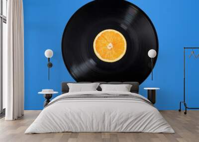 Vinyl record with orange fruit in the centre. Flying in the air. Isolated on blue background. Surrealism levitation concept. Wall mural