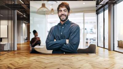 Im always on top of my game. Portrait of a young businessman standing in an office with his colleagues in the background. Wall mural