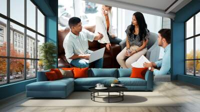 Bringing together their ideas to craft something amazing. Shot of a group of businesspeople having a discussion in an office. Wall mural