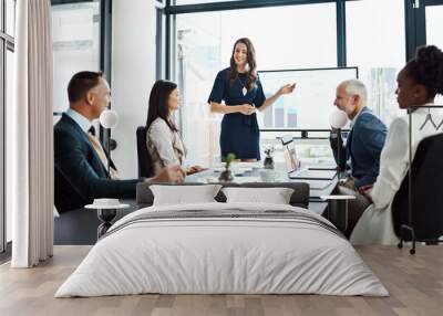 Business woman speaker in an investment meeting with financial data on a boardroom screen. International executive team listening to a presentation. Finance worker talking at a partnership proposal Wall mural