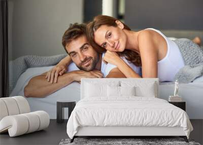 Going outside is so overrated. Shot of a happy young couple relaxing in bed together at home. Wall mural