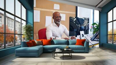 Making it another successful day. Shot of a mature businessman working on a computer in an office. Wall mural