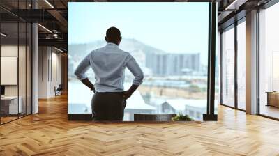 This city inspires me to keep upping my game. Rearview shot of a businessman looking out the window in an office. Wall mural