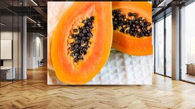 Bright orange exotic papaya fruit halved slices with black seeds on light background. Wall mural