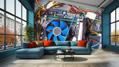 Old blue cooler fan with motherboard and colorful cables inside a computer. Wall mural