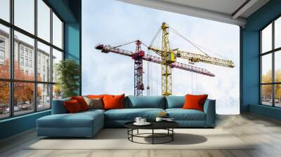 Two high cranes for house building at construction site on blue sky background. Wall mural