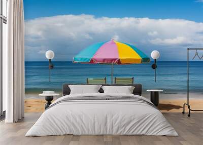 Two beach chairs and an umbrella on a tropical beach with white, soft sand and clear, blue water. The sky has fluffy white clouds, creating a peaceful and relaxing scene of paradise. Wall mural