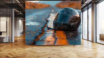 A broken black motorcycle helmet lying on the side of an empty road Wall mural