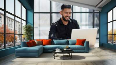 Bearded young businessman working on modern office. Consultant man thinking looking in monitor computer Wall mural