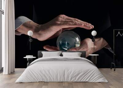 businessman's hands are covered with a glass ball on a black background Wall mural