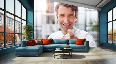 Businessman sitting on the table and pointing at you Wall mural