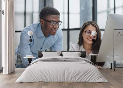 Cheerful multiracial colleagues discussing startup project and smiling during workday in office interior Wall mural