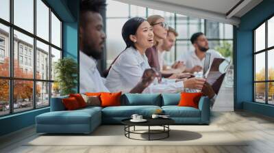 Multicultural colleagues sitting at desk near digital devices and documents during business meeting Wall mural