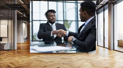 Shot of two young business men shaking hands in a modern office Wall mural