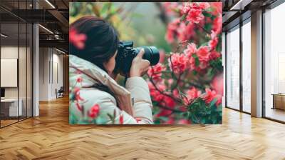 Girl photographing flowers in a garden with vibrant blooms. Wall mural