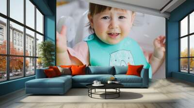 A small child is sitting at the table and eating Wall mural