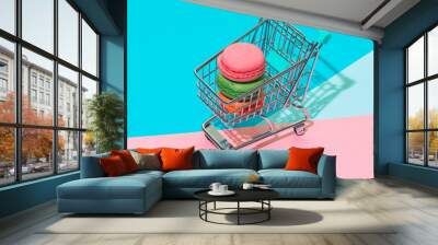 Colorful almond cookies macarons or macaroons in shopping cart on memphis style background. creative concept of dessert, sharp shadows Wall mural