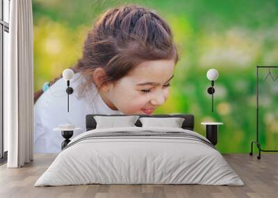 beautiful little girl blowing dandelion flower and smiling in summer park. happy cute kid having fun Wall mural