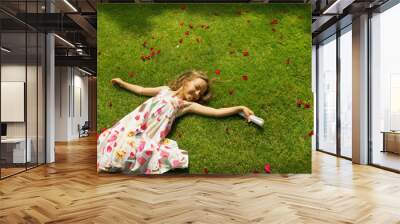 little girl resting on a green grass Wall mural