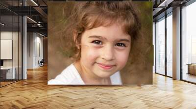 Portrait of smiling beautiful little girl at green of summer park.Cute child looking at the camera Wall mural